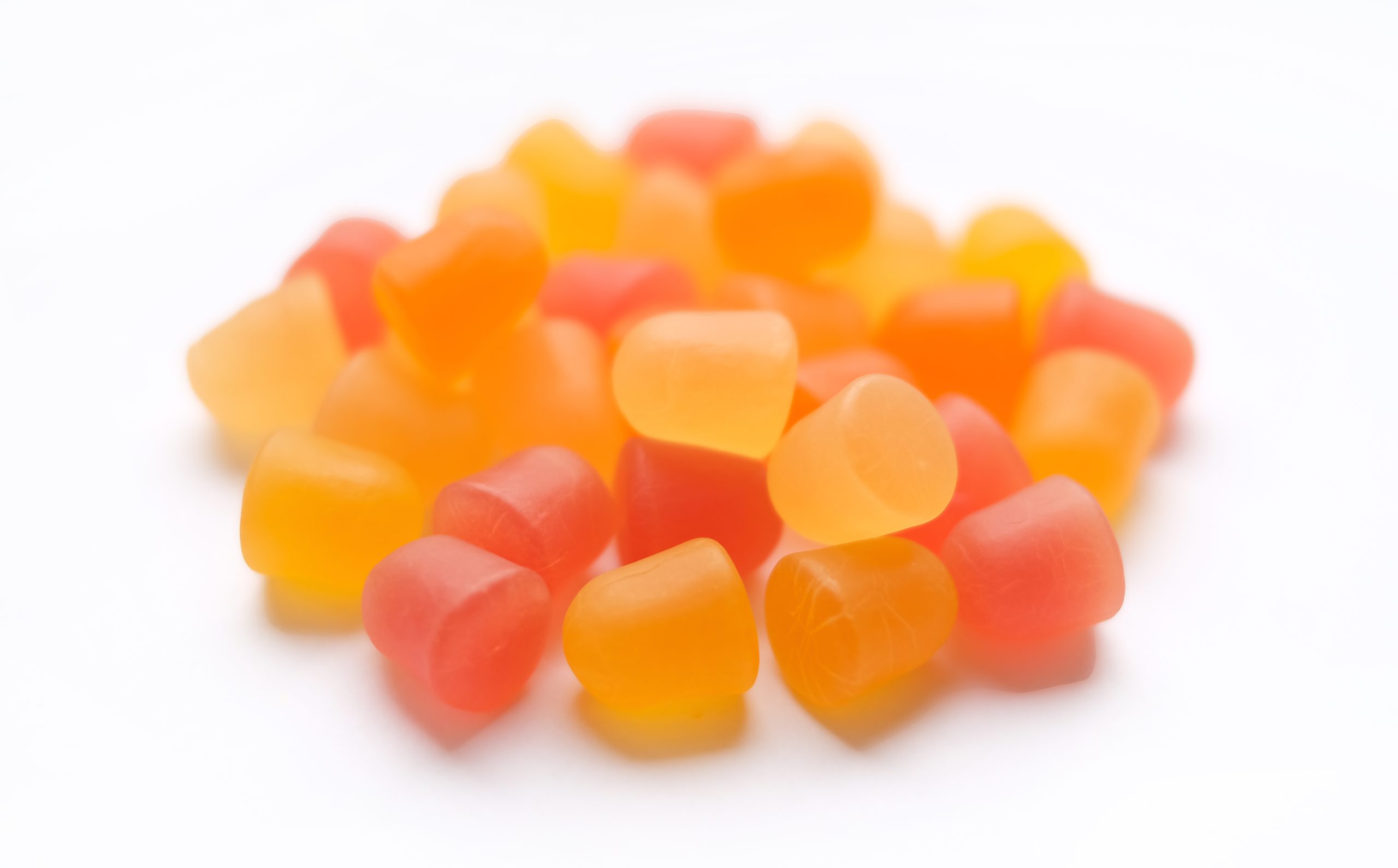 Close-up texture of orange and yellow multivitamin gummies in the form of bears on white background. Healthy lifestyle concept.